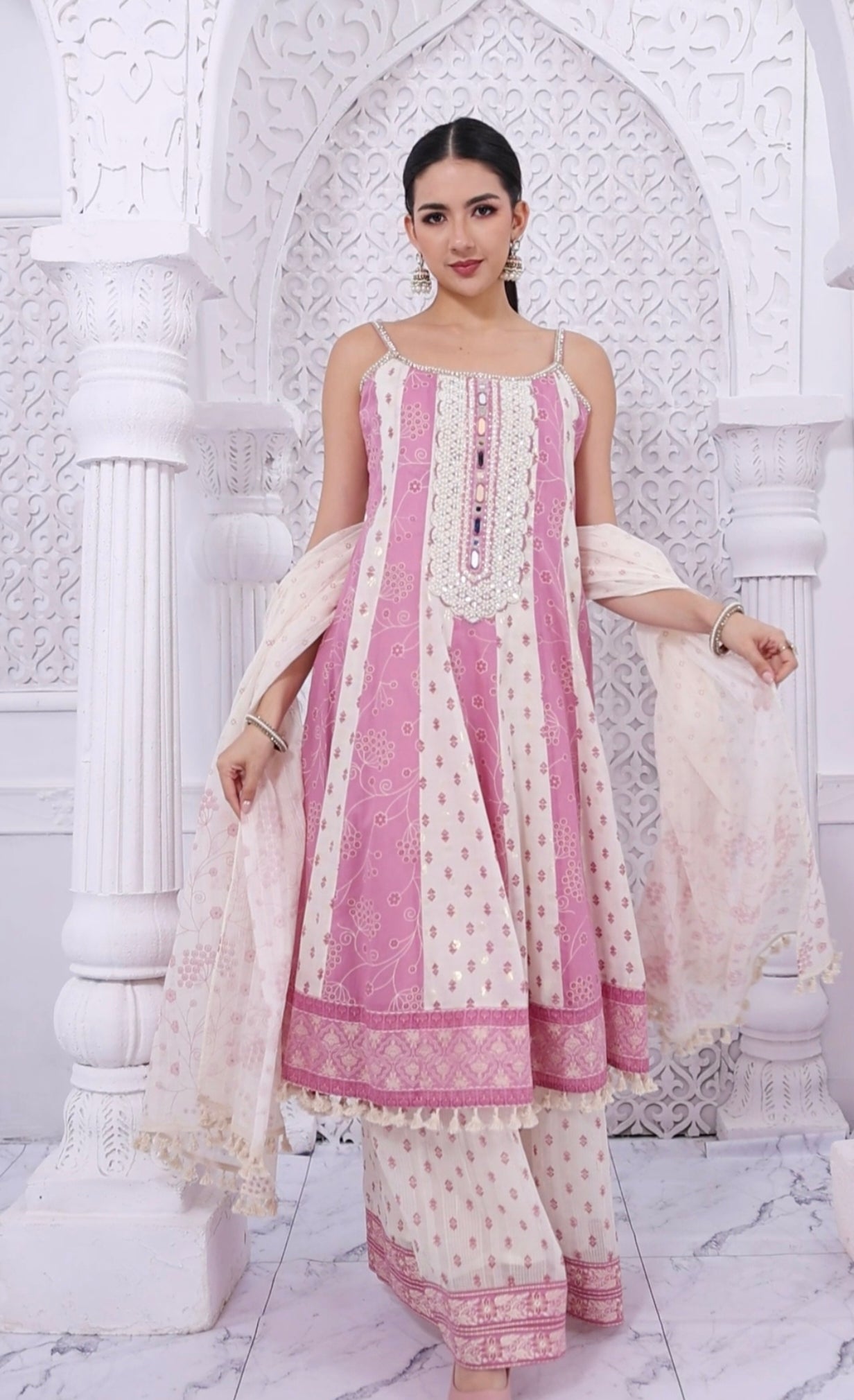 Woman wearing a pink and white traditional outfit in a decorative setting