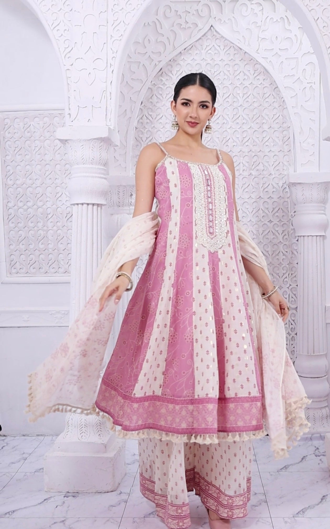 Woman wearing a pink and white traditional outfit in a decorative setting